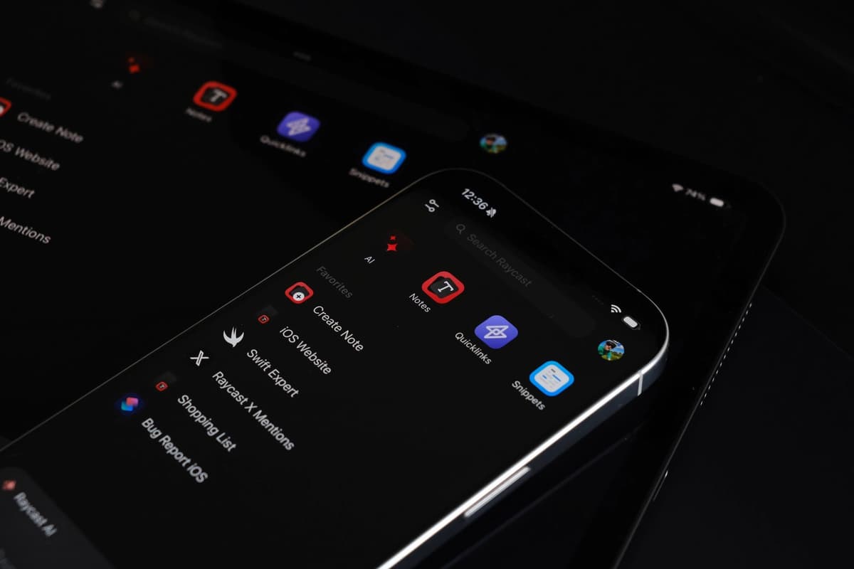 Picture of an iPhone placed above an iPad displaying the home screen of the Raycast iOS app